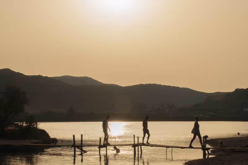 Tramonto sul lago con figure su un pontile