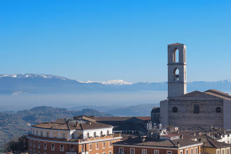 Skyline di Perugia con campanile e montagne innevate